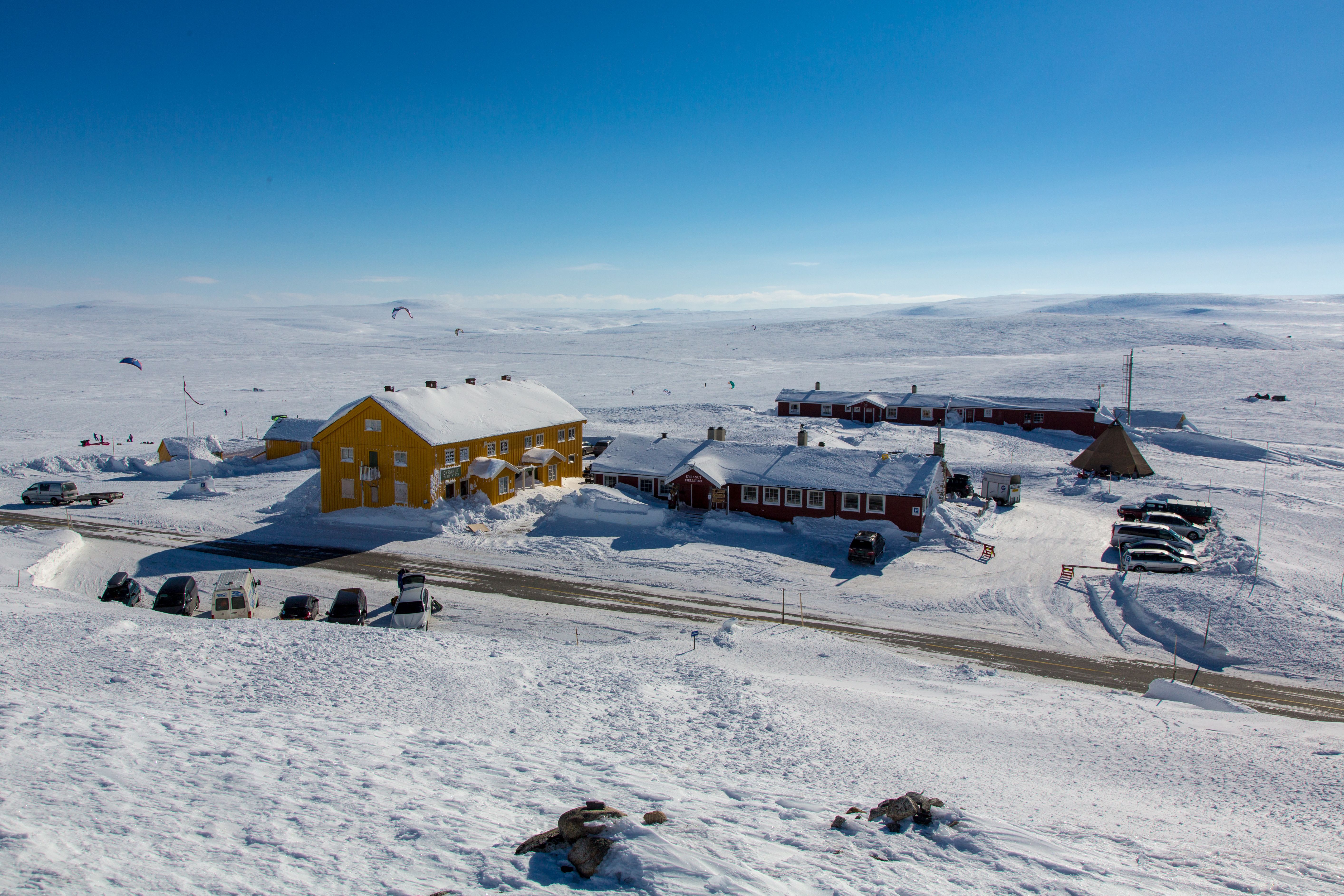 The red Dyranut Fjellstova and yellow Dyranut Turisthytta mountain lodges in snowy landscape.