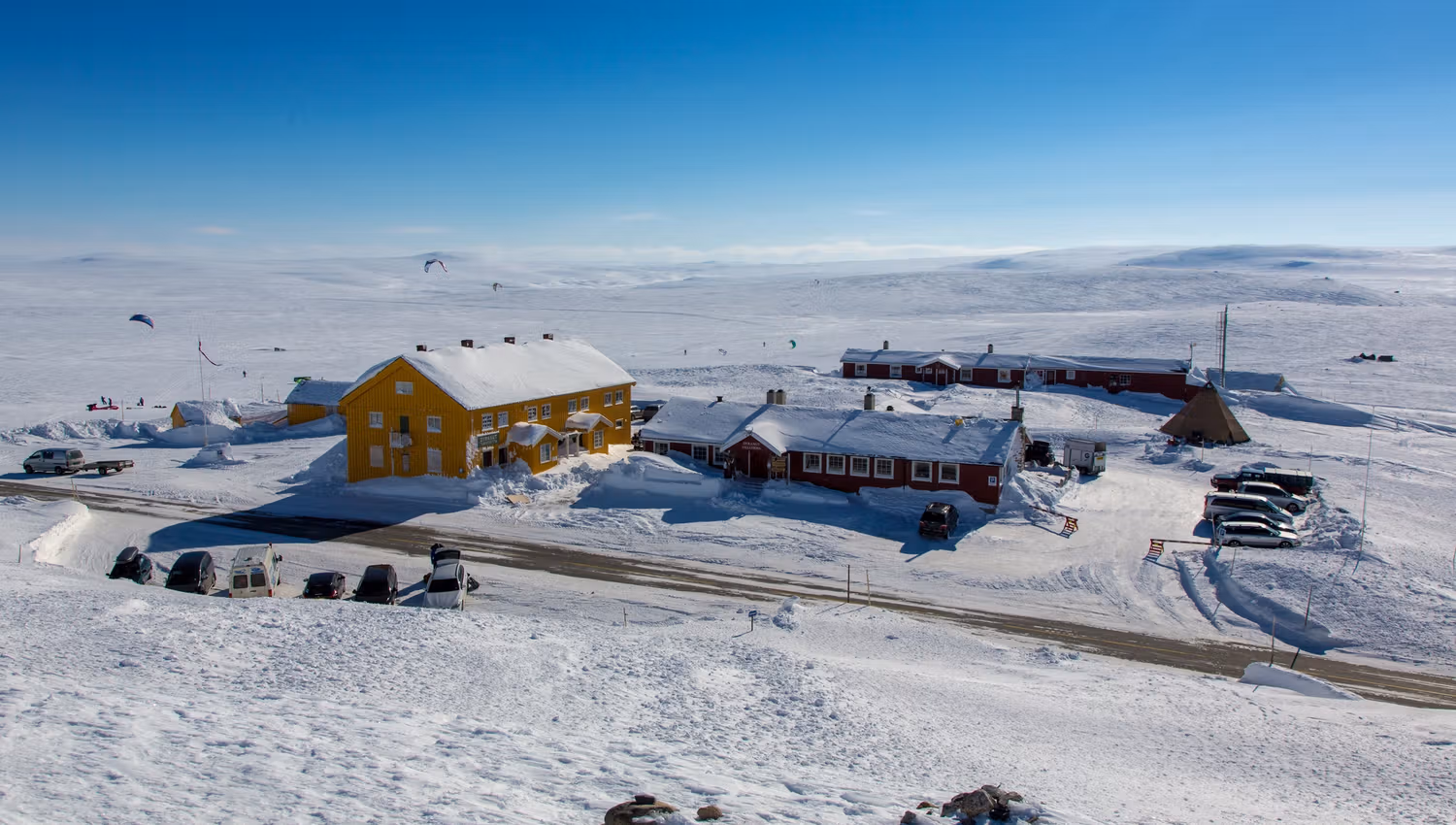 The red Dyranut Fjellstova and yellow Dyranut Turisthytta mountain lodges in snowy landscape.