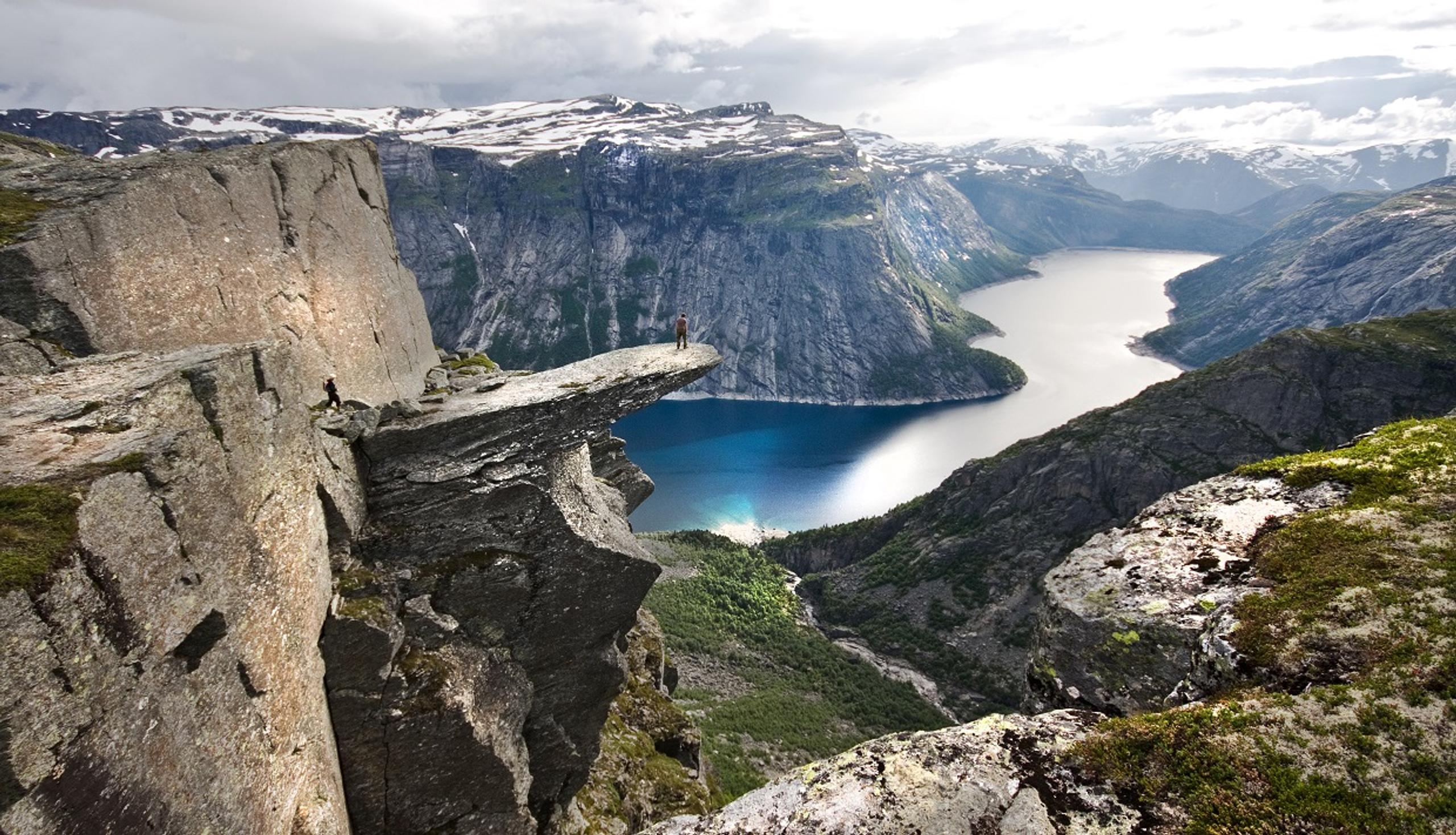 A photo of a person standing at the tip of Trolltunga.