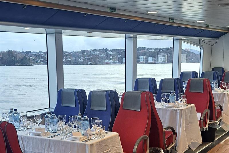 Set tables inside a boat with views overlooking the fjord