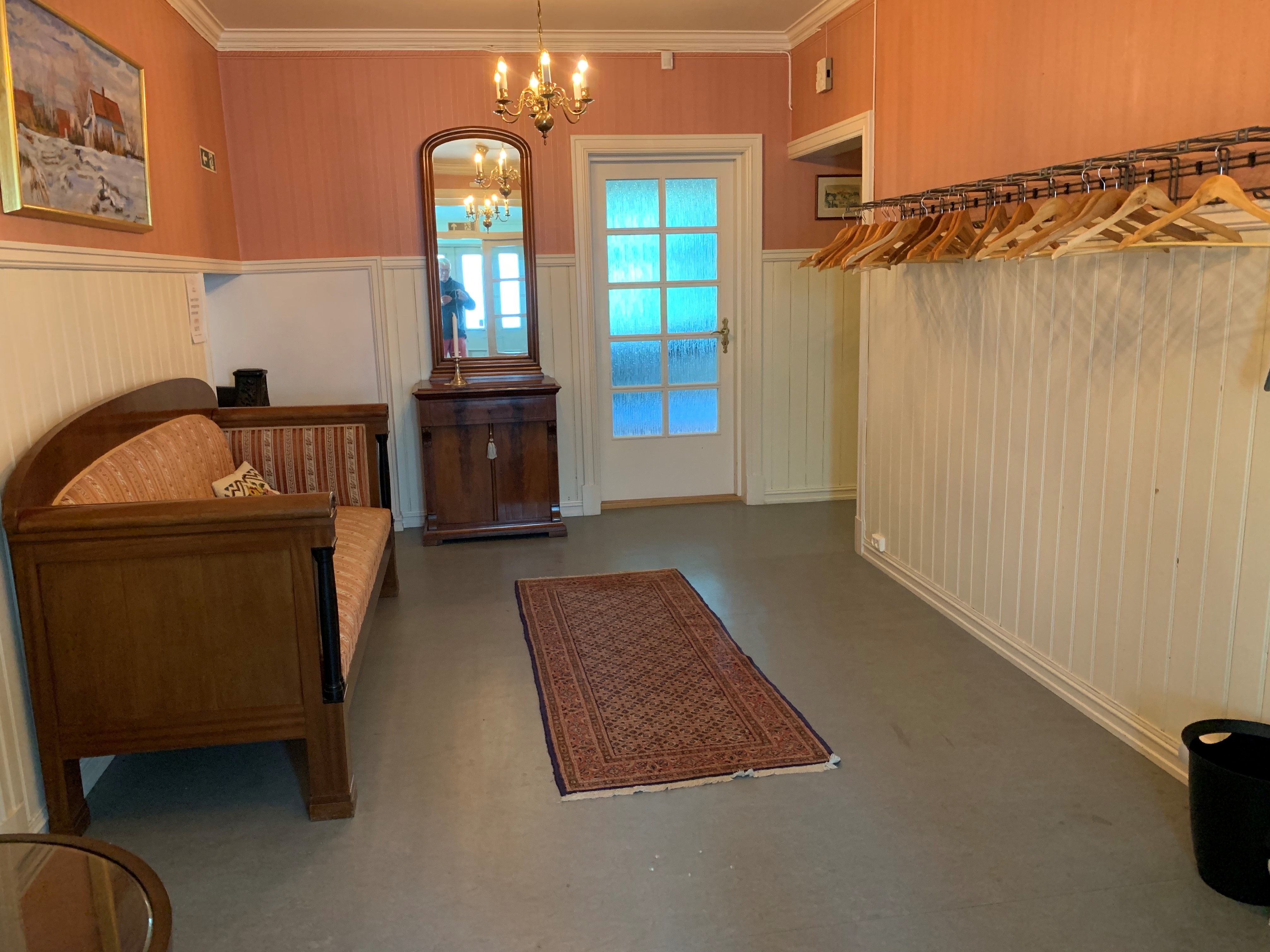 Garderobe med plasser til å henge jakke og en sofa.