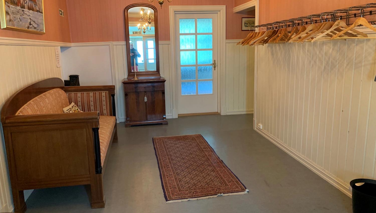 Garderobe med plasser til å henge jakke og en sofa.