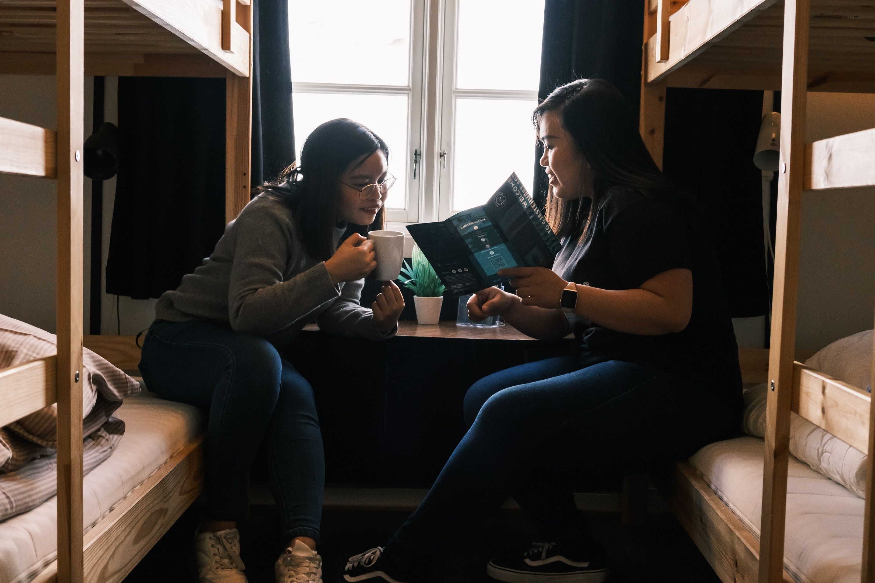 Two persons sitting in bunk beds talking to each other.