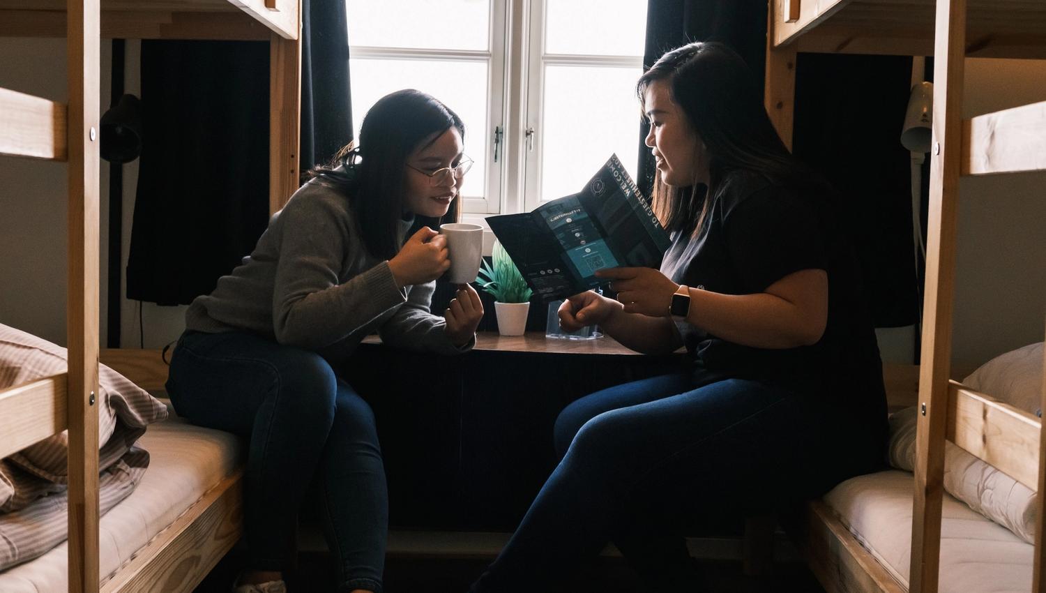 Two persons sitting in bunk beds talking to each other.