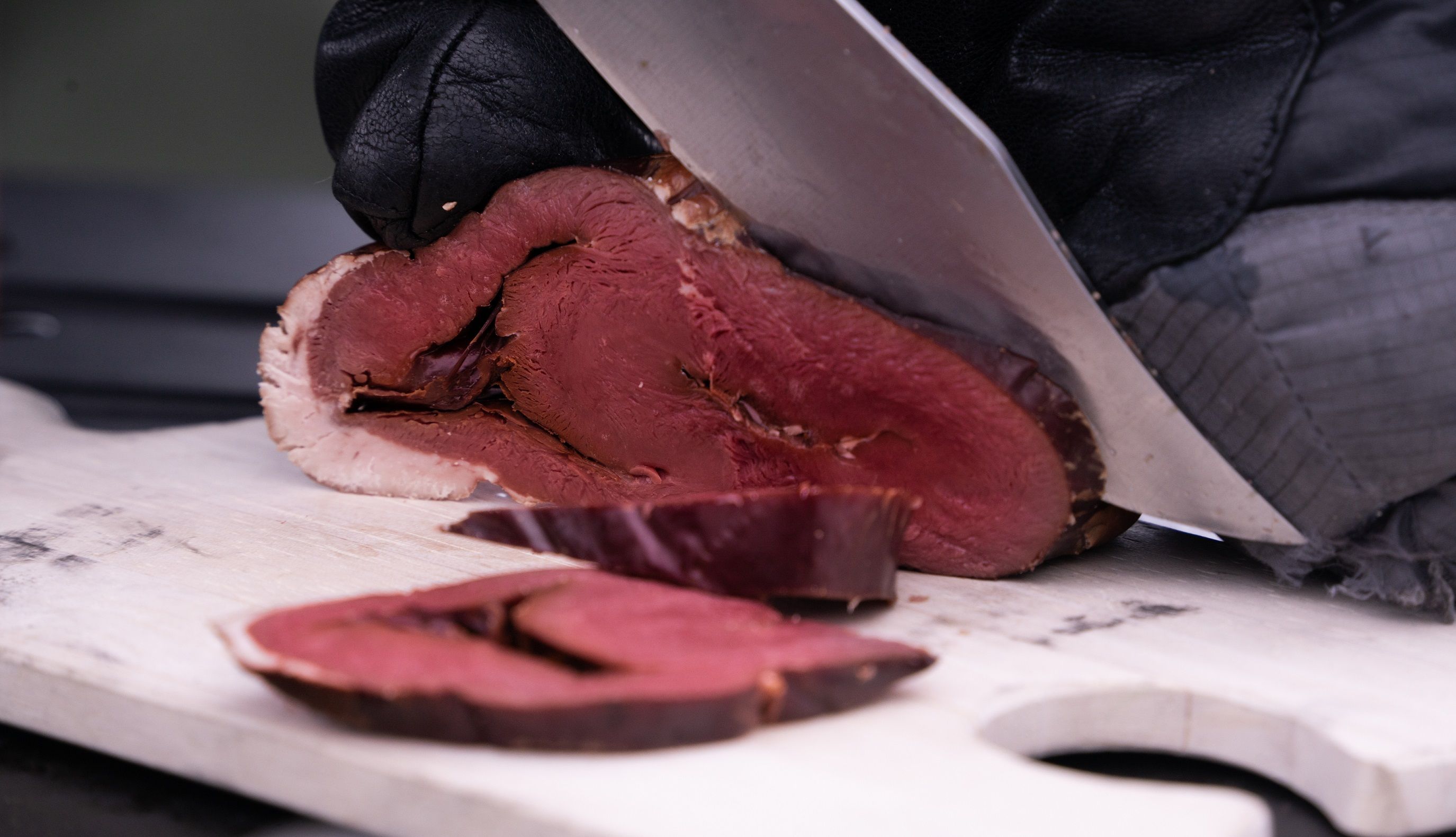 Meat being sliced with a knife on a cutting board