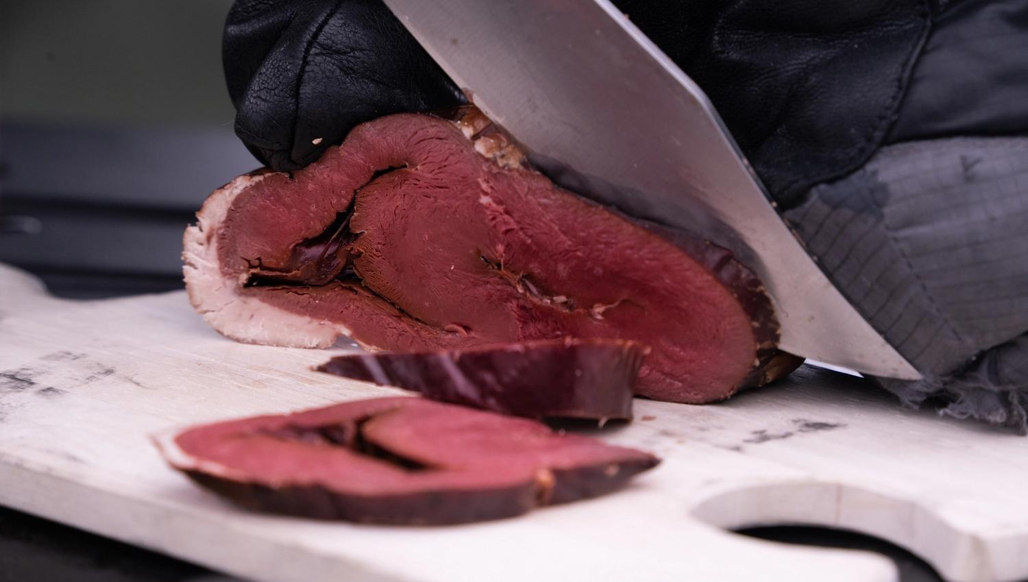 Meat being sliced with a knife on a cutting board
