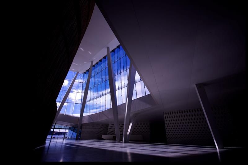 Interior photo of a high ceiling with big glass windows.