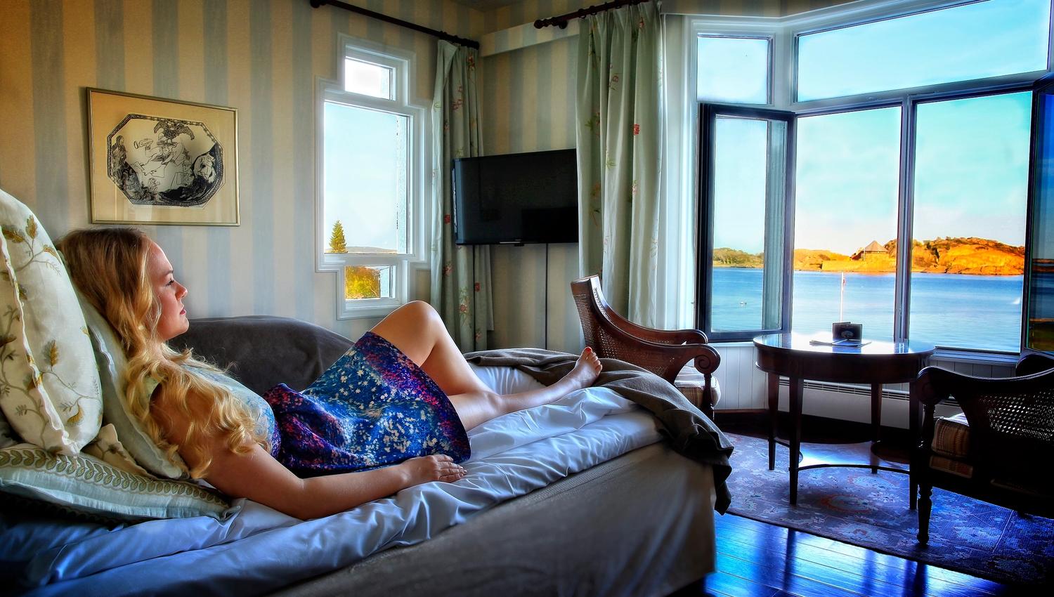 One who relaxes in bed and looks out the window at the view