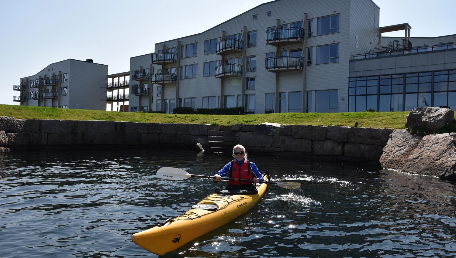 Blid kvinne i en gul kajakk utenfor Lindesnes Havhotell