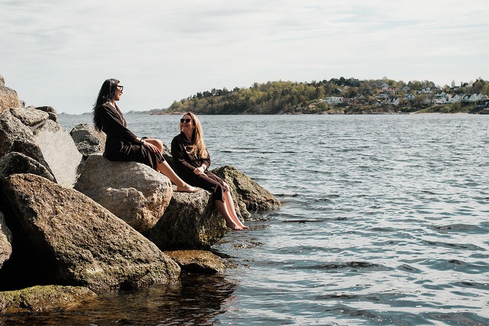 two people sits by the ocean