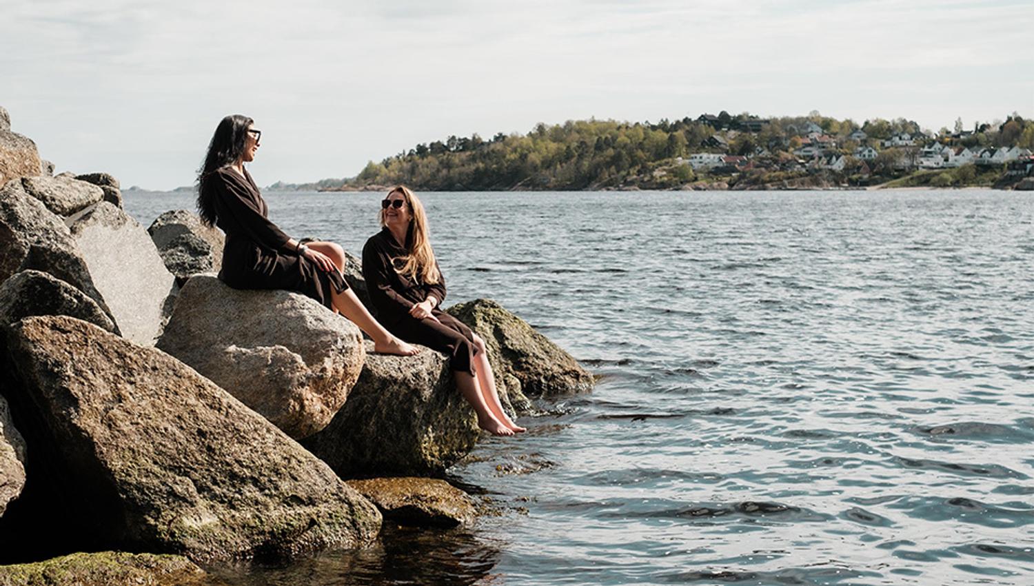 two people sits by the ocean