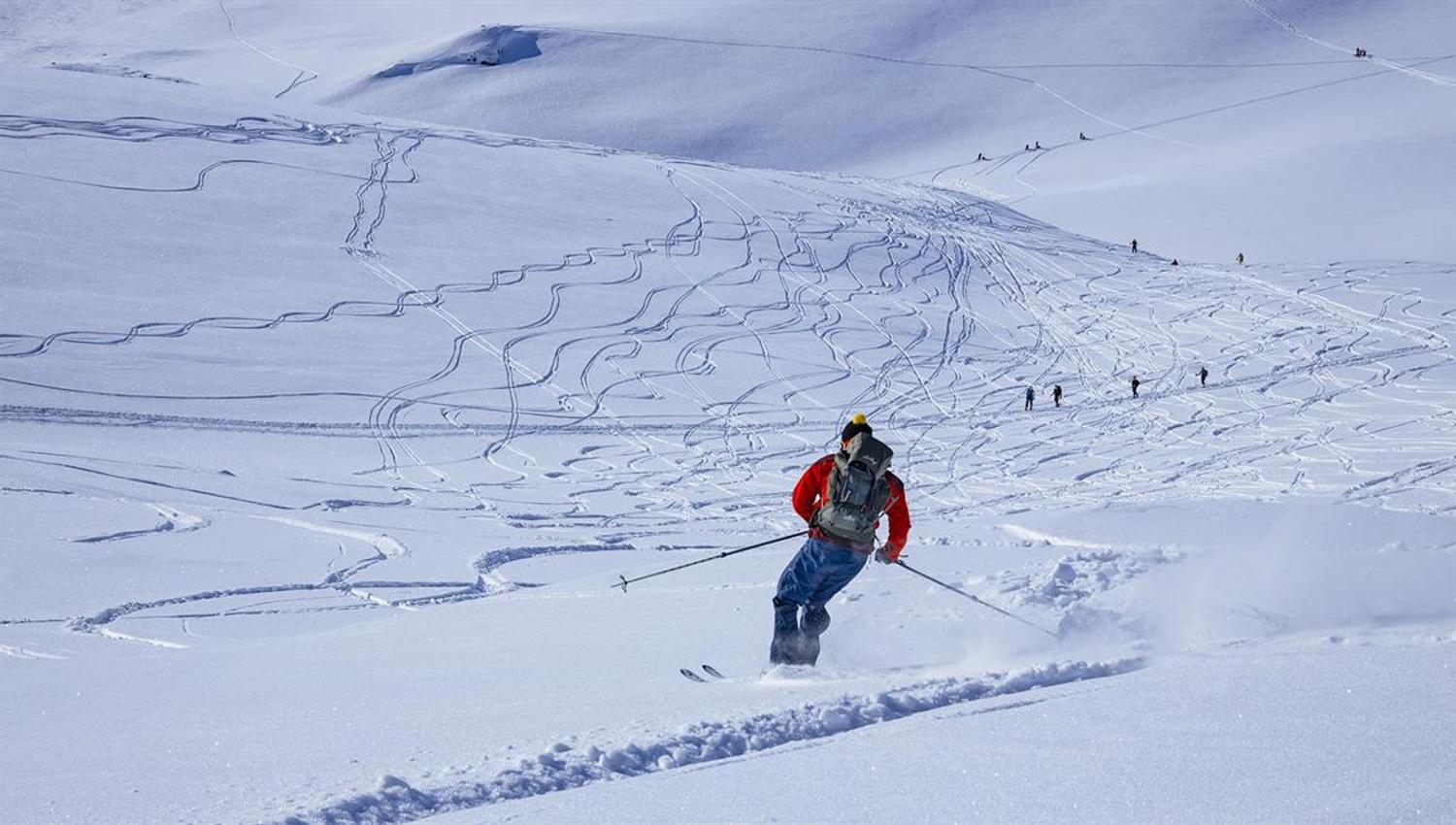 Person on the way down a mountain on randonee skis.