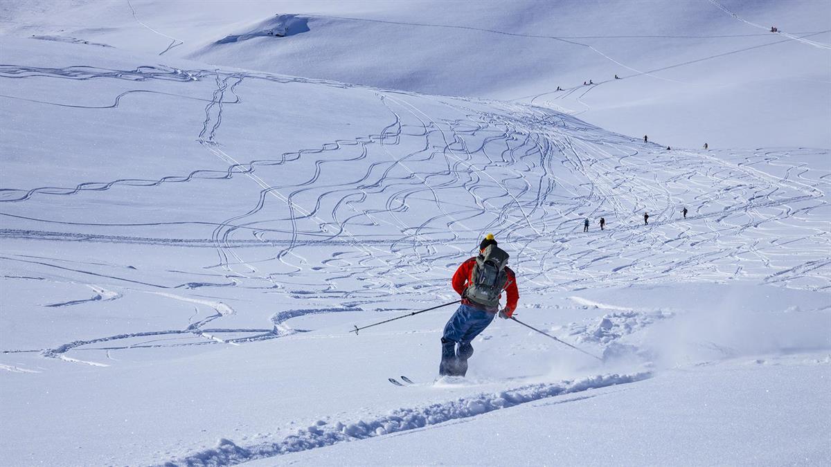 Person on the way down a mountain on randonee skis.