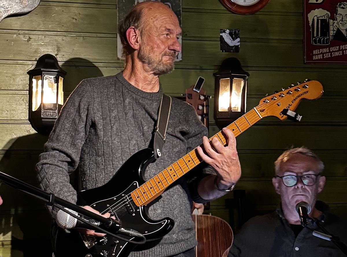 Sanger med gitar underholder i en Pub