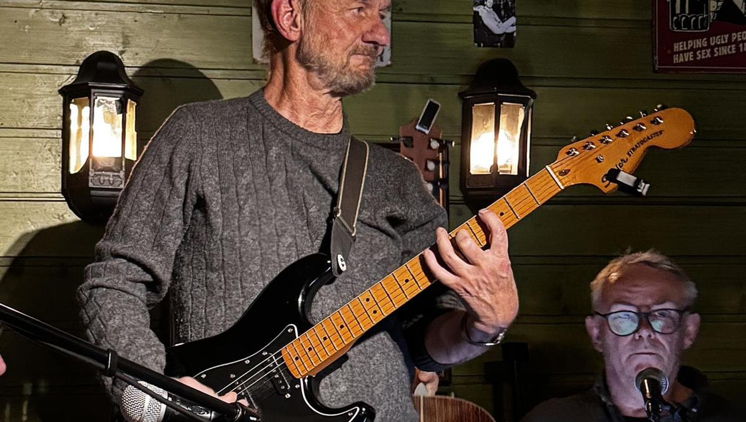 Sanger med gitar underholder i en Pub