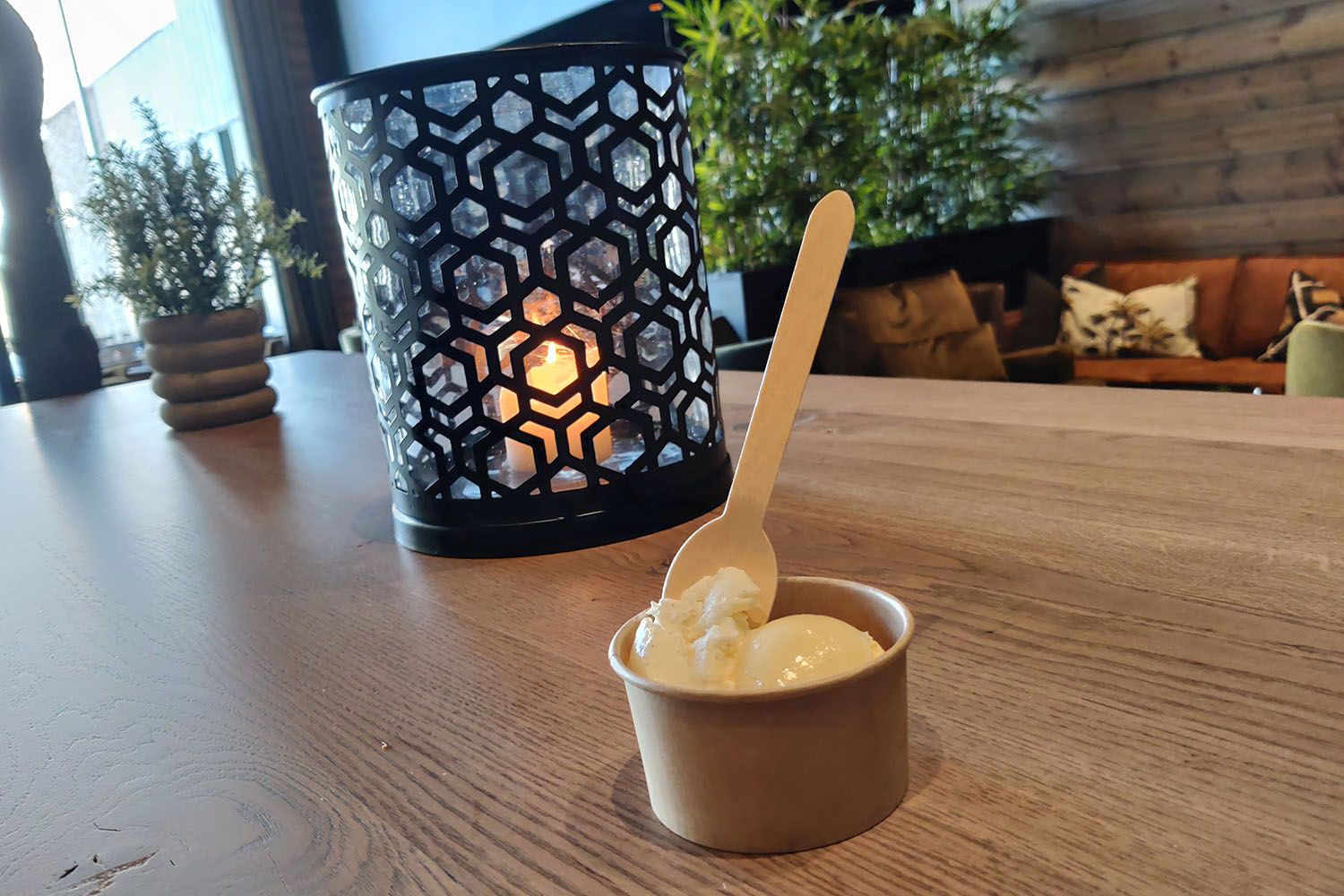 Candle in a candle holder and an ice cream cup on a restaurant table