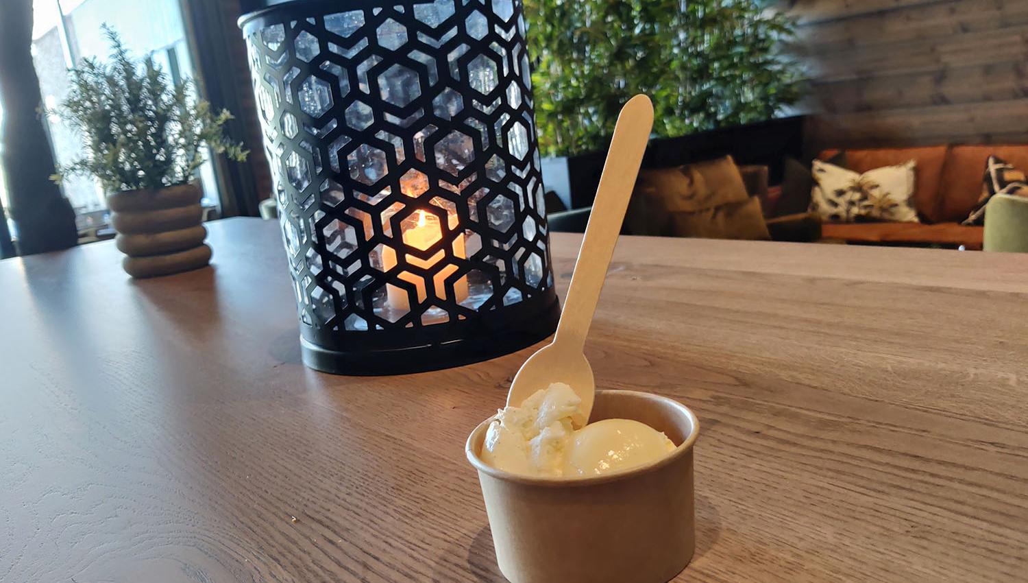 Candle in a candle holder and an ice cream cup on a restaurant table