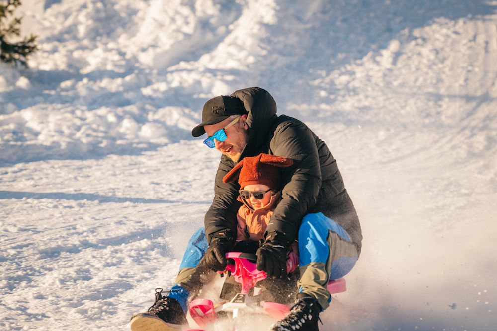 man with small child on a sled at Lifjell ski center in Bø 