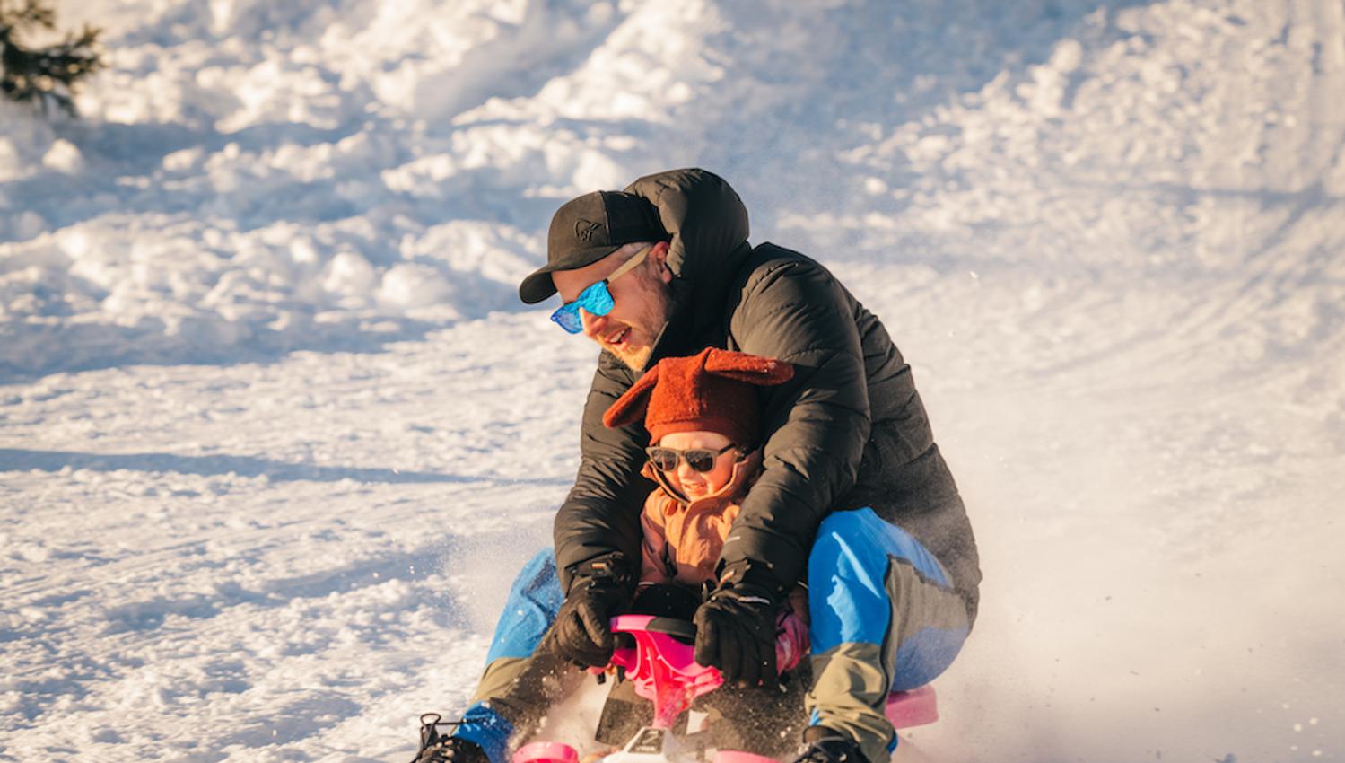 man with small child on a sled at Lifjell ski center in Bø