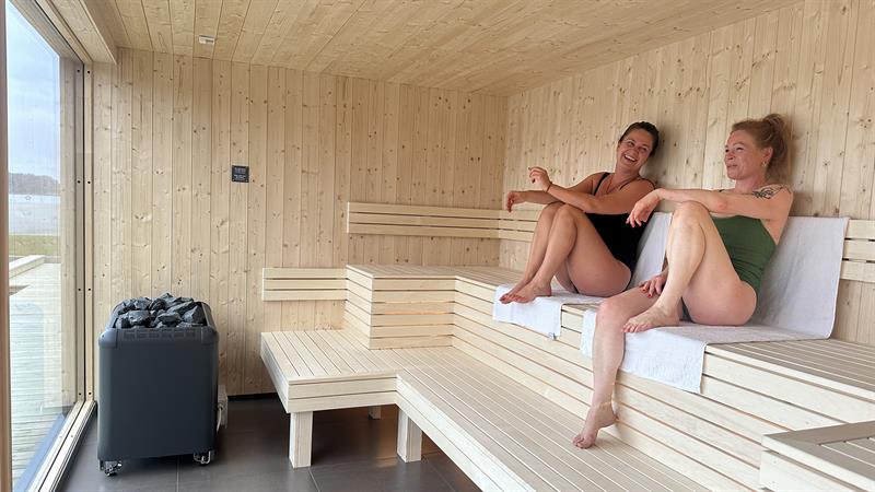 Two people smiling and enjoying themselves in the sauna.
