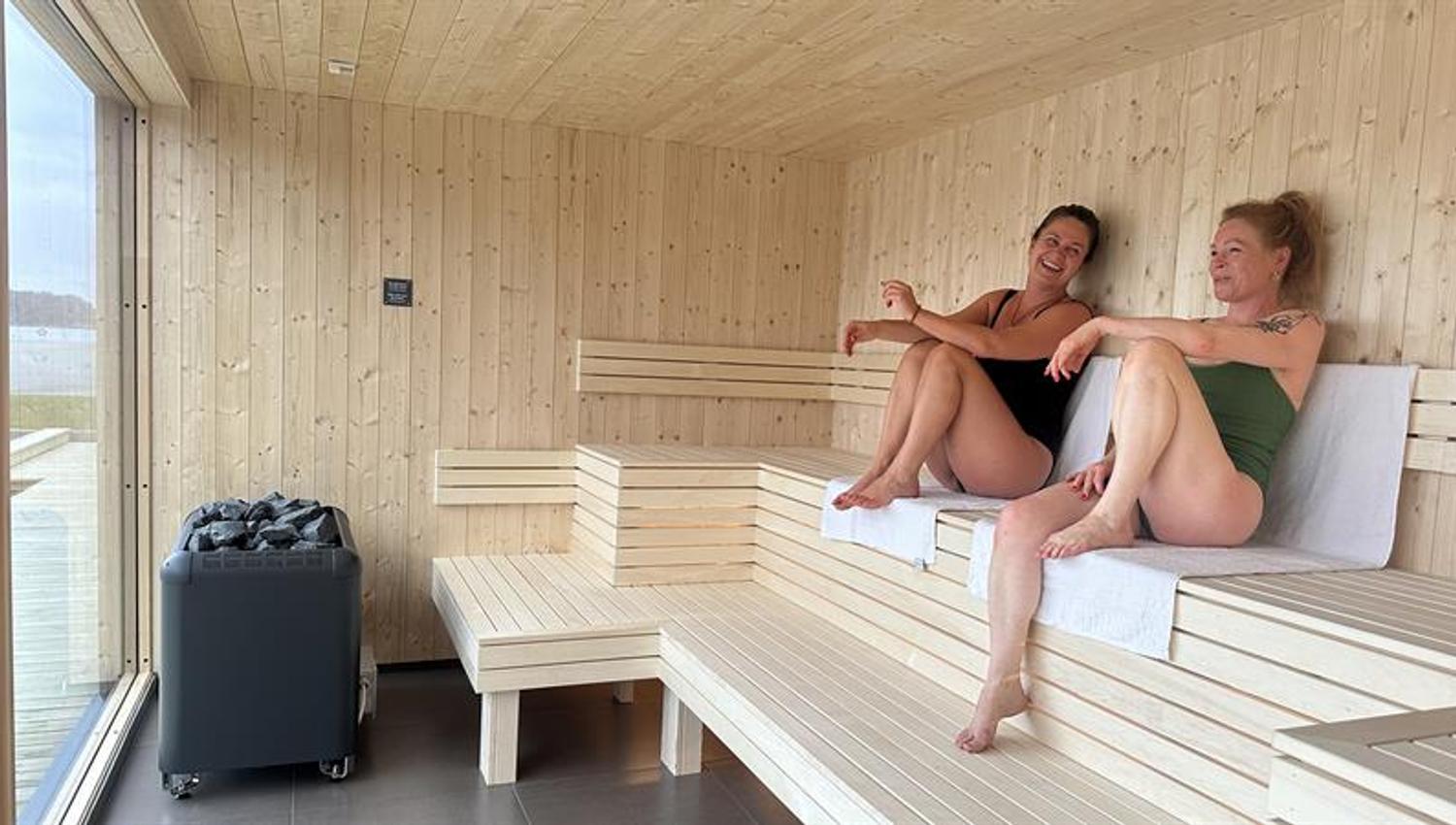 Two people smiling and enjoying themselves in the sauna.