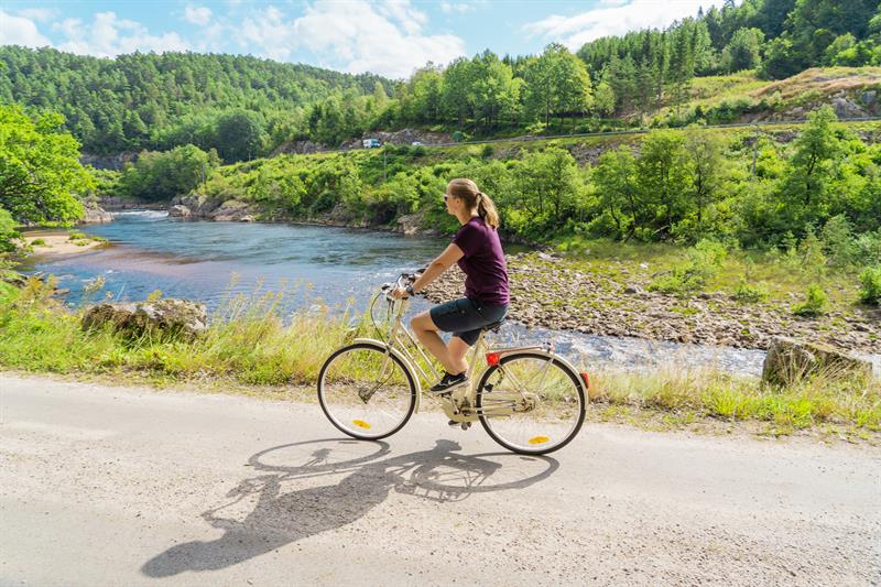 En syklende dame på grusvei lands Mandalselva