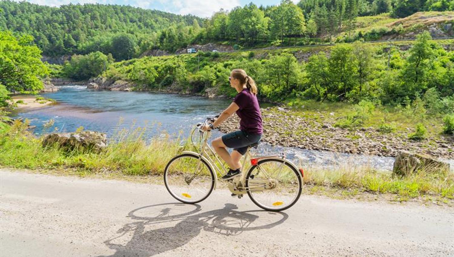 En syklende dame på grusvei lands Mandalselva