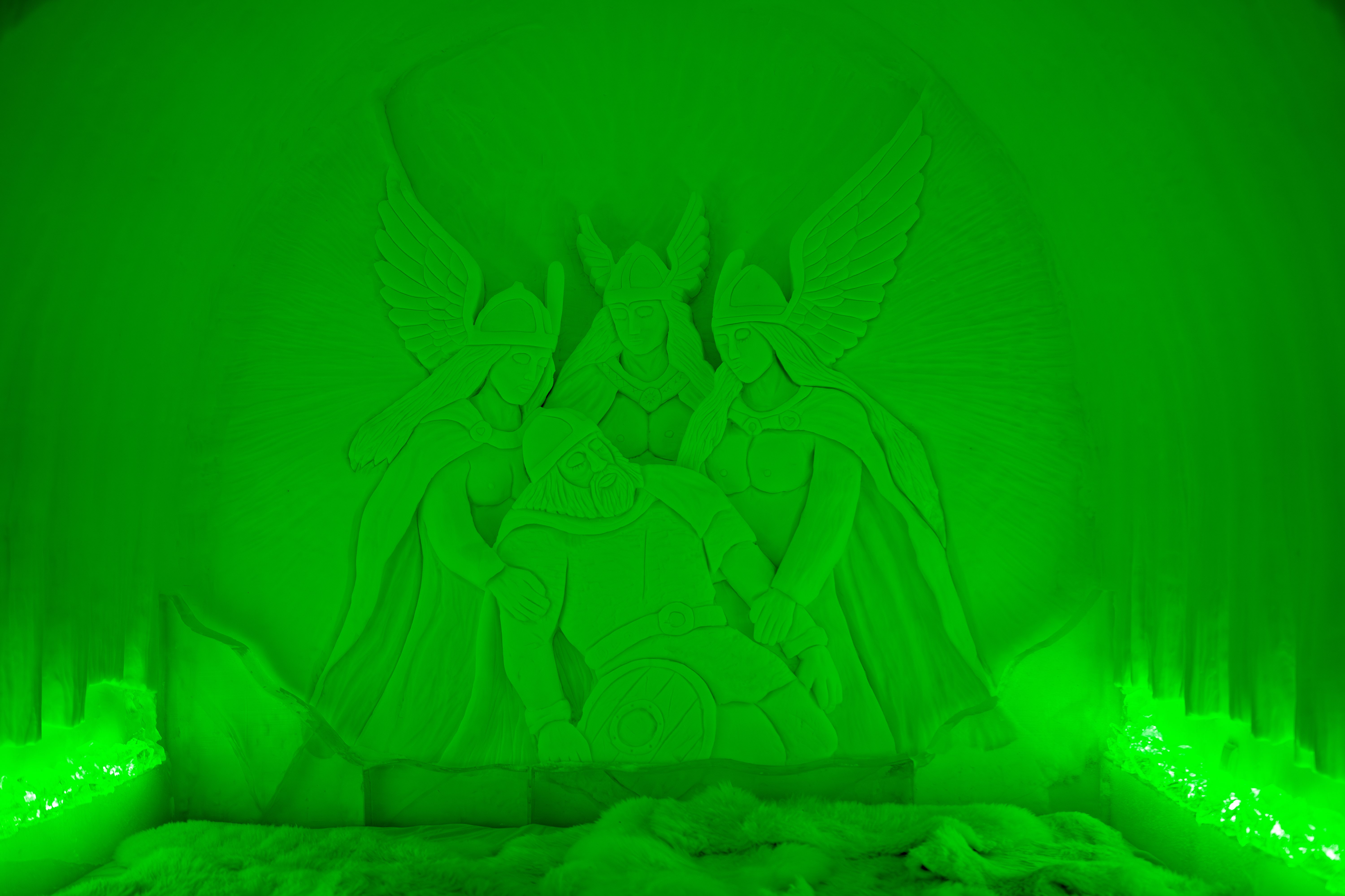 Ontdek deze indrukwekkende sneeuwsculptuur, verlicht in een betoverend groen licht. De afbeelding toont mythologische figuren die een held omringen, wat een gevoel van mystiek en avontuur oproept. Een must-see voor elke bezoeker!