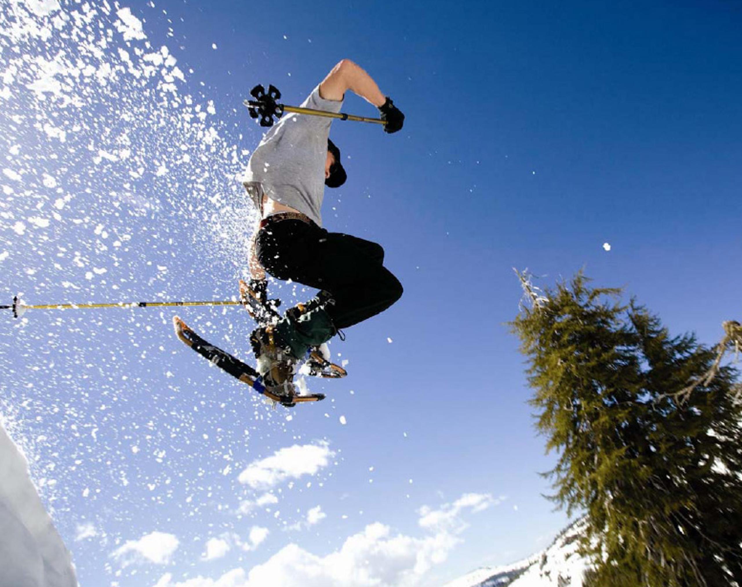 Person jumping with snowshoes and the snow is flying