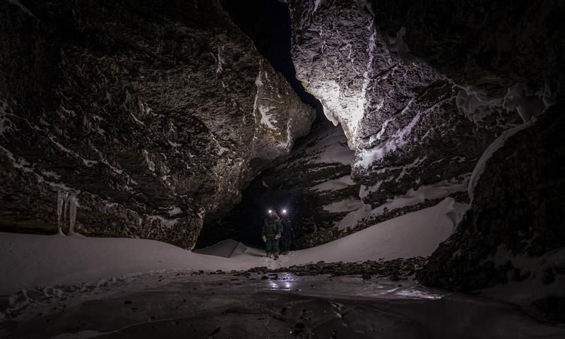 Two people walking in a valley with headlamps on
