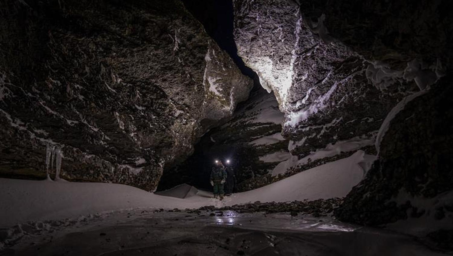 Two people walking in a valley with headlamps on