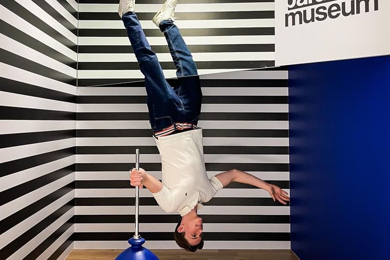 Boy floating upside down, striped walls in the background.