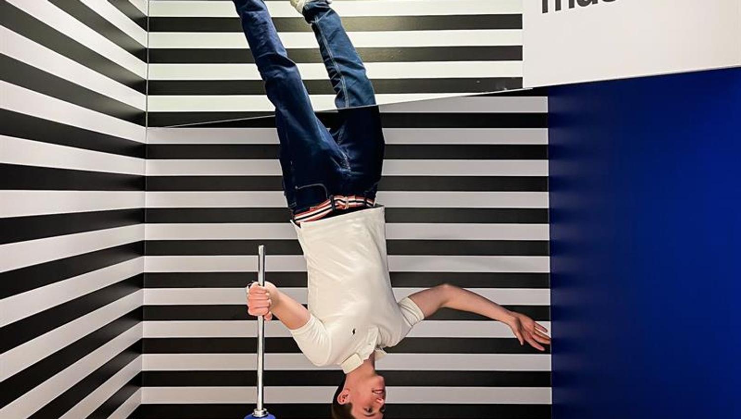 Boy floating upside down, striped walls in the background.