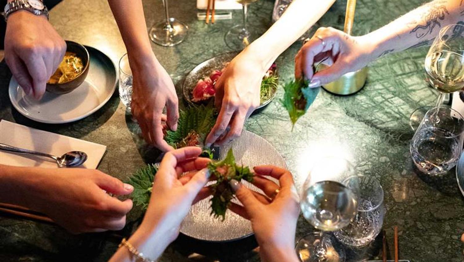 Hands reaching for a sharing menu