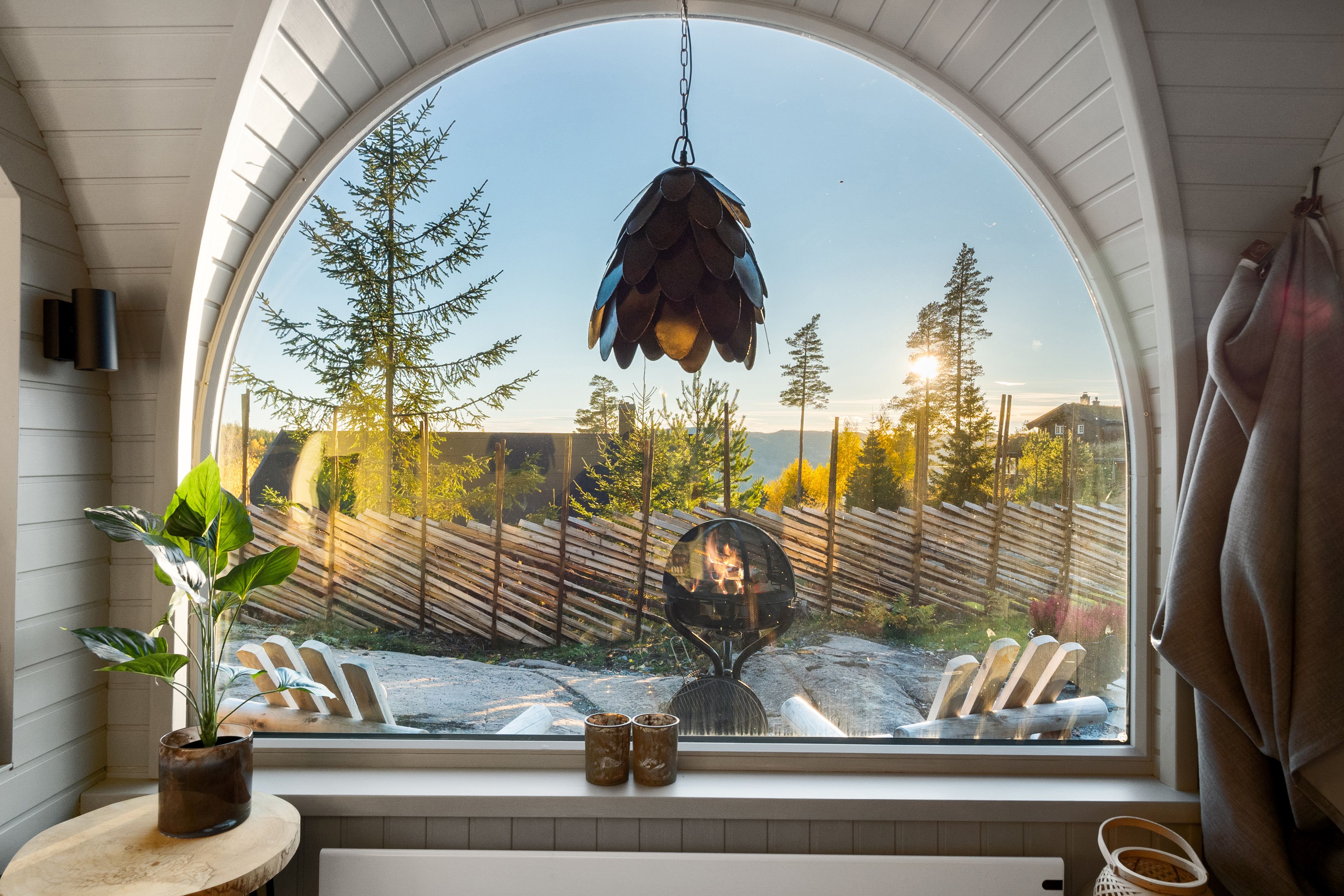 Interior photo from a cabin with a large window, chairs and a bed, and a view.