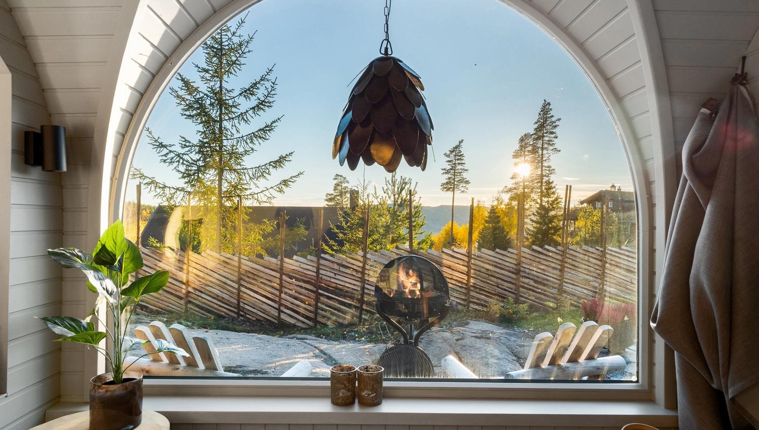 Interior photo from a cabin with a large window, chairs and a bed, and a view.