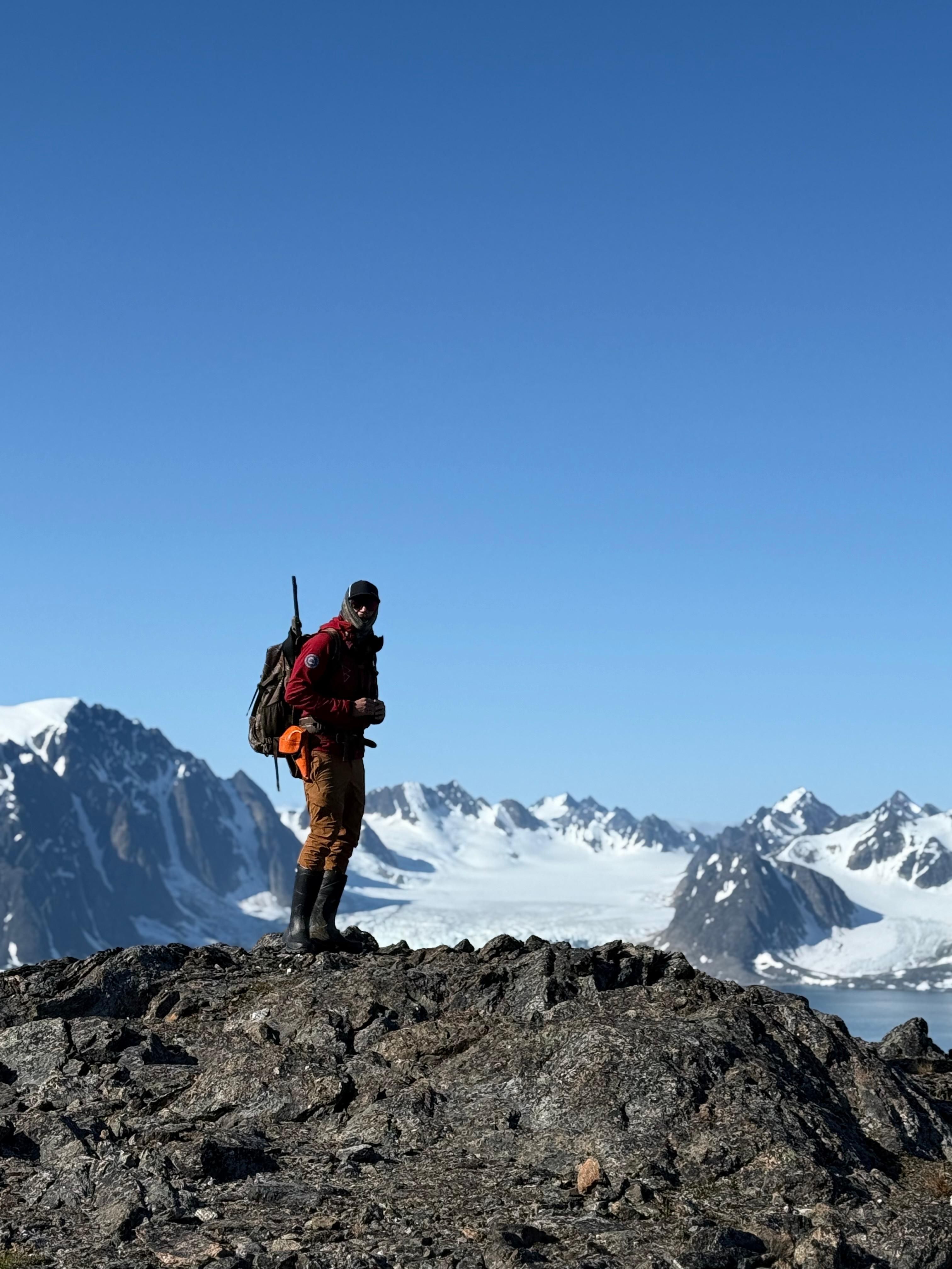 En guide på en fjelltopp med majestetiske fjell i bakgrunnen