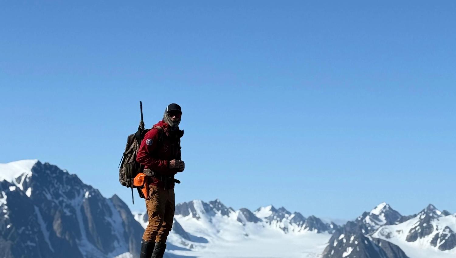 En guide på en fjelltopp med majestetiske fjell i bakgrunnen
