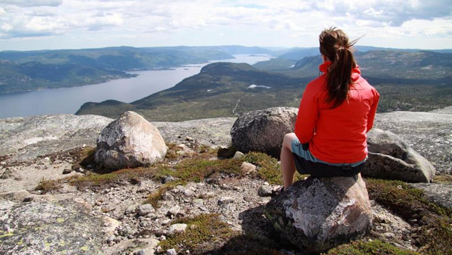 jente sitter på toppen av Hægefjell og nyter utsikten