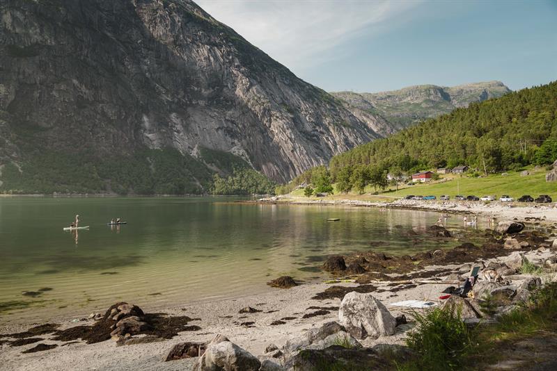 Stavanes beach on a sunny day, filled with people both on the beach and in the fjord.