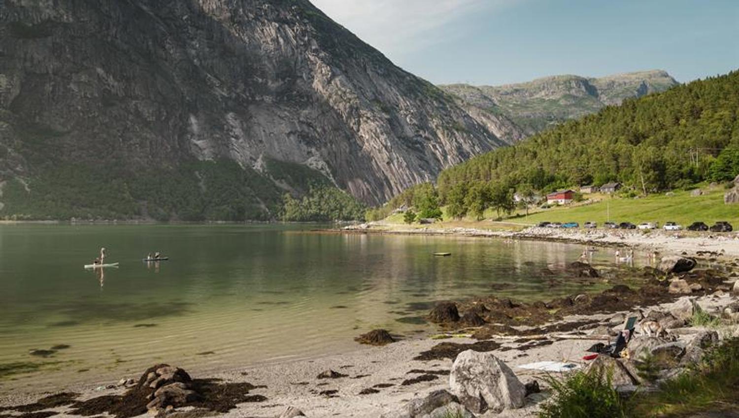 Stavanes beach on a sunny day, filled with people both on the beach and in the fjord.
