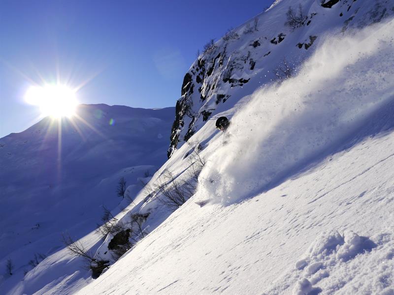 Freerider gleitet durch tiefen Pulverschnee im Sonnenuntergang im Røldal Skigebiet.