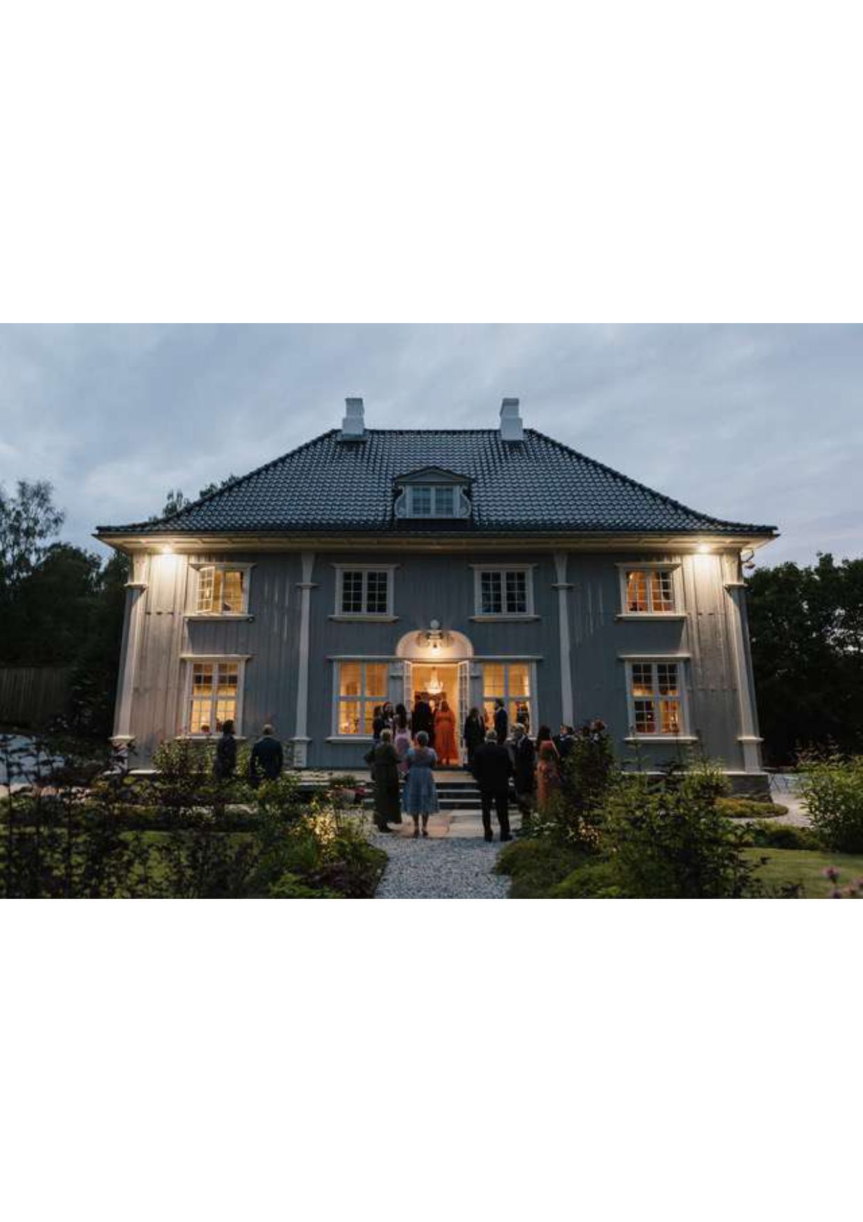gjester foran et herskapshus i skumring