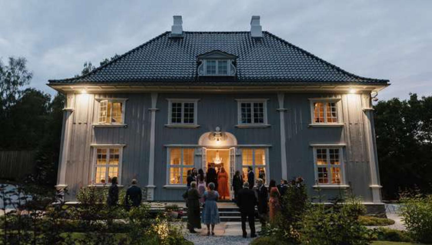 gjester foran et herskapshus i skumring