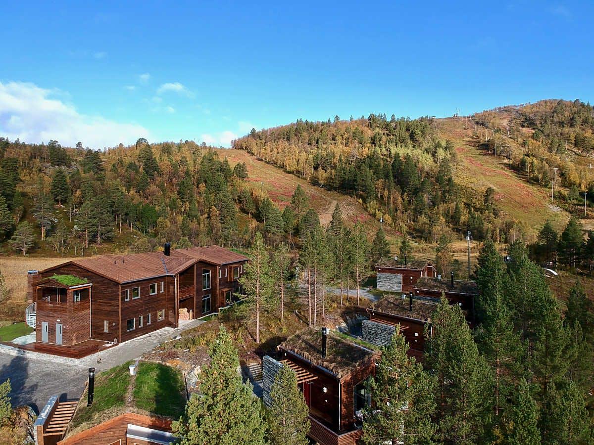 Aperçu d'un complexe hôtelier en bois, entouré de forêts colorées en automne.