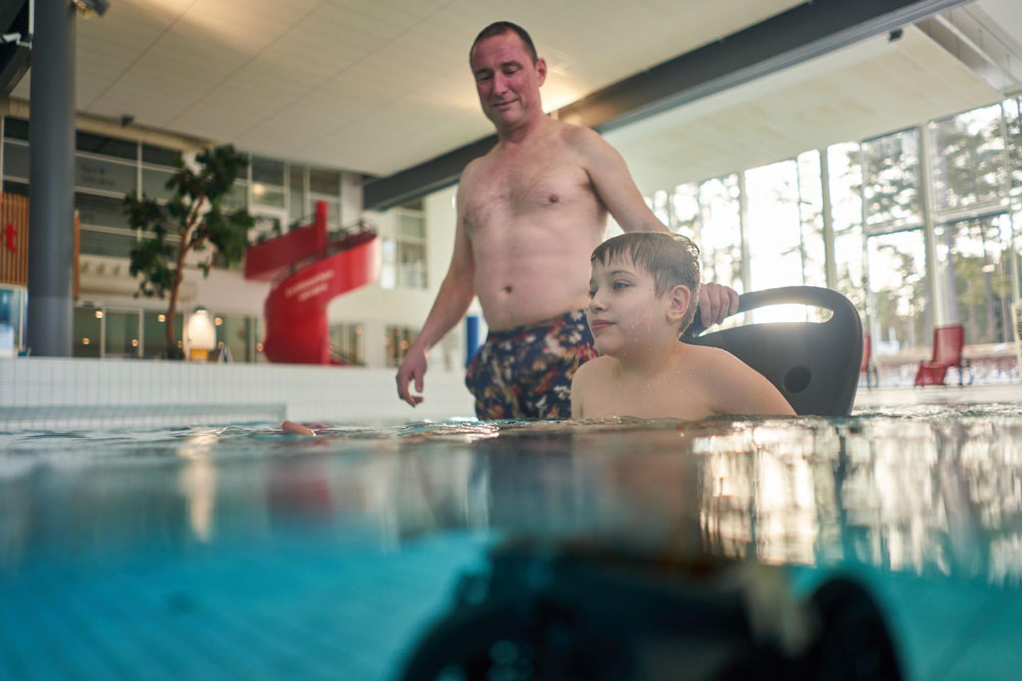 far og sønn i rullestol i badebasseng i Skien  fritidspark