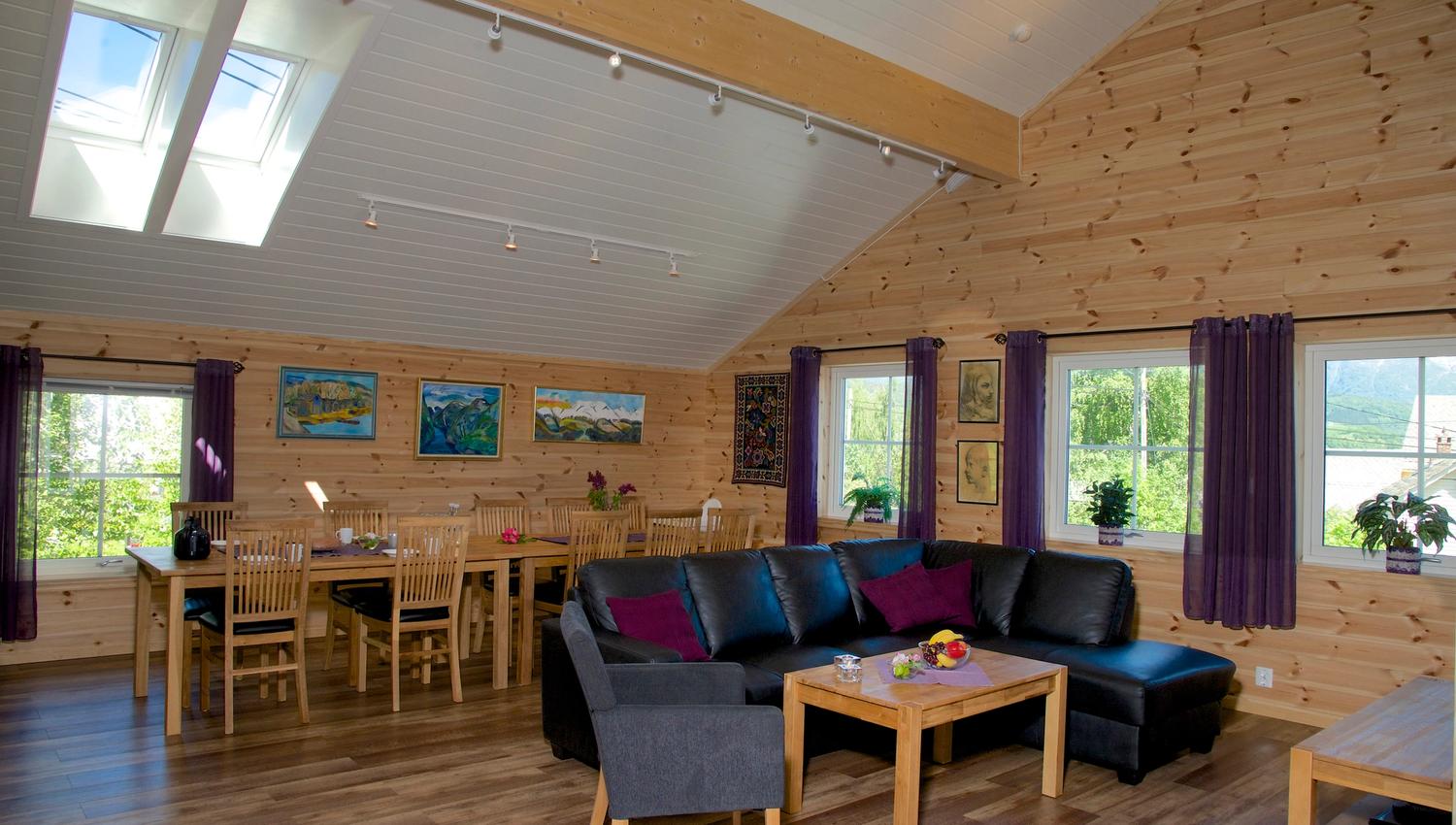 Bright and spacious living room with dining table, modern sofa and large windows at Vågen Rom og Hytteutleige in Hardanger.