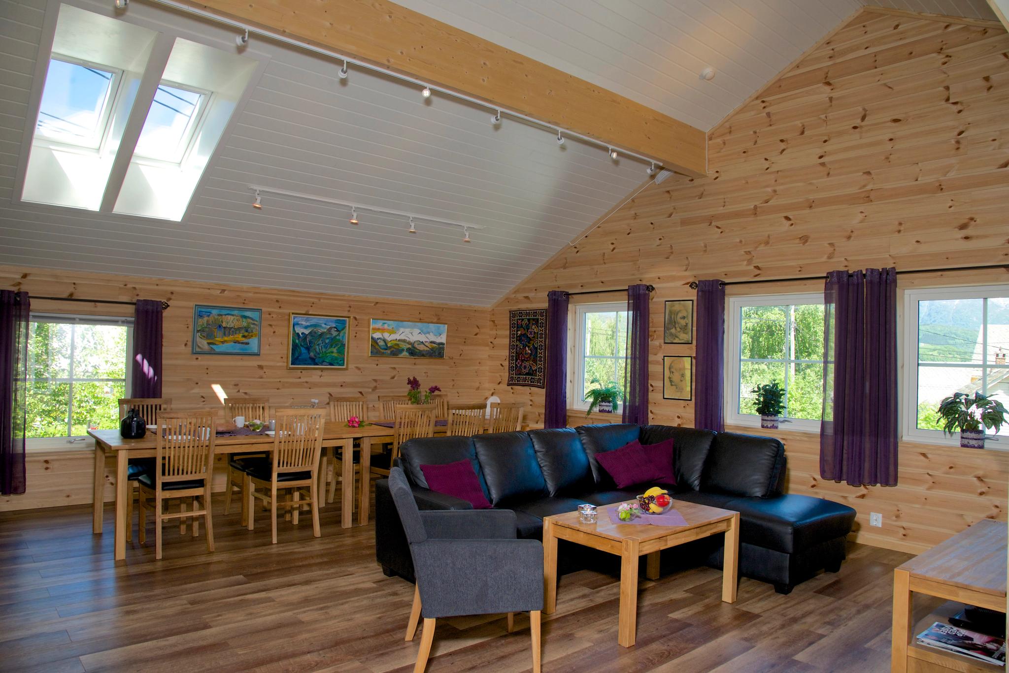 Bright and spacious living room with dining table, modern sofa and large windows at Vågen Rom og Hytteutleige in Hardanger.