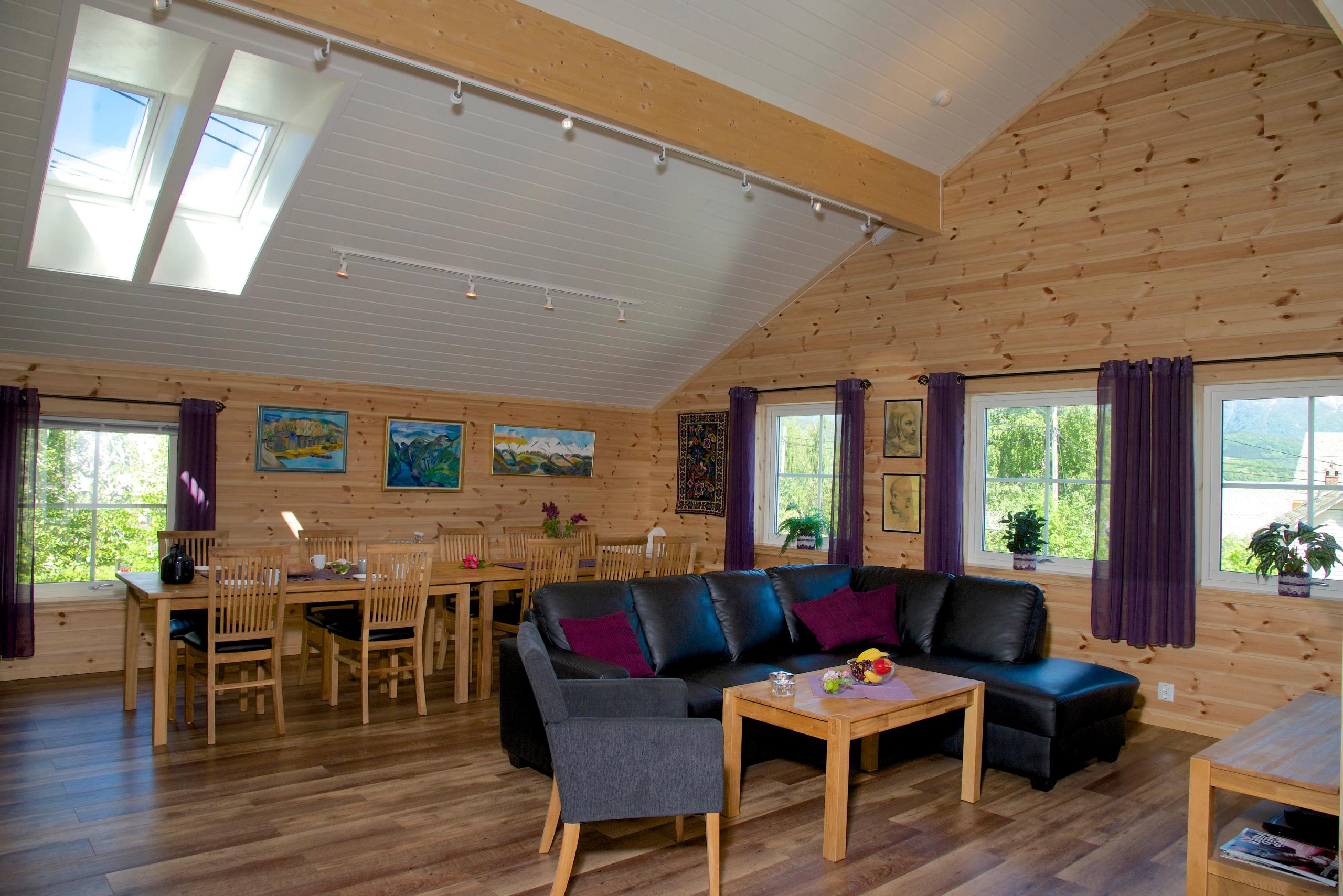 Bright and spacious living room with dining table, modern sofa and large windows at Vågen Rom og Hytteutleige in Hardanger.