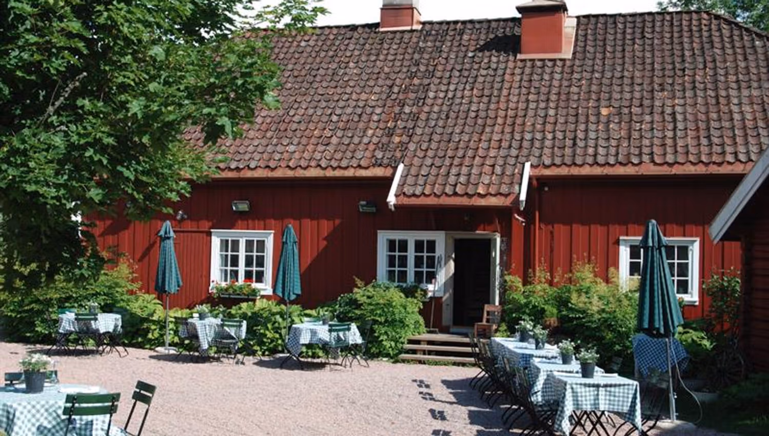 Rødt hus og dekket bord i bakhage